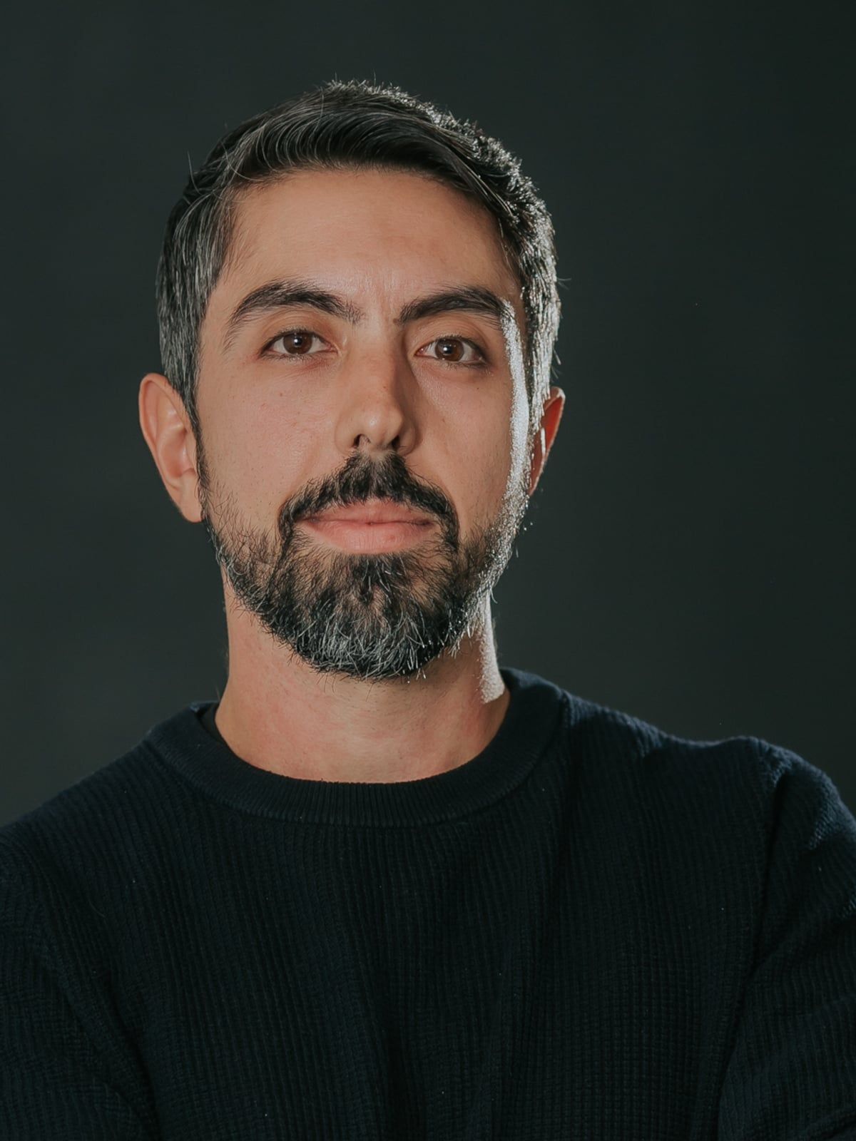 Retrato de Gabriel Motta em estúdio, de suéter escuro, olhando para a câmera