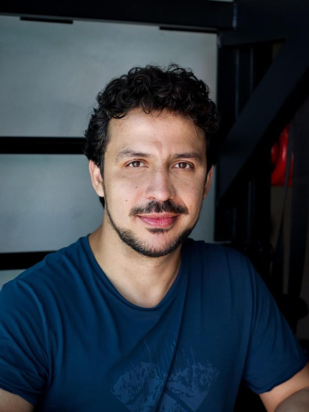 Retrato de Lucas Araújo sorrindo, de camiseta, em ambiente interno